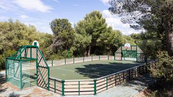 Una cancha de tenis al aire libre rodeada de árboles.