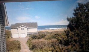 A house with a garage, a pathway leading to the entrance, and a view of the ocean.