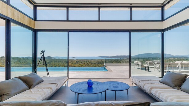 Una habitación moderna con pared de vidrio, piscina y vistas al paisaje.
