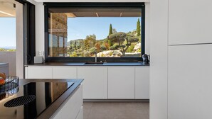 Cocina moderna con un ventanal grande, armarios blancos y encimera negra.