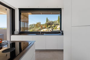 A modern kitchen with a large window, white cabinetry, and a black countertop. - Villa "Alba" with Sea View, Wi-Fi, and Air Conditioning (Zonza)