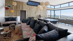 Una sala de estar moderna con un sofá grande, un tapete estampado y un comedor con vistas panorámicas.