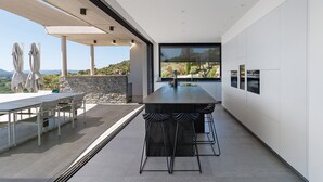 Una cocina moderna con una isla grande, taburetes de bar y vistas al exterior.