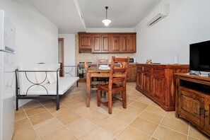 Une cuisine de taille réduite avec des meubles en bois, une table à manger avec des chaises, un canapé et un téléviseur.