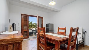 A dining area with a wooden table and chairs, a refrigerator, and a television. - Apartment 'Bella Vista Su Tavolara 4' with Tavolara View, Wi-Fi and Air Conditioning (Porto San Paolo)
