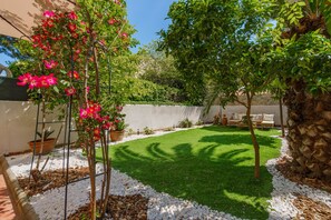 A garden with a lawn, trees, and outdoor furniture.