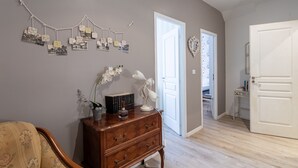 Una habitación con un aparador de madera, un expositor de fotos en la pared, una puerta y una pequeña mesa con libros.