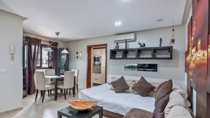 Een moderne hotelkamer met een bed, zithoek, eethoek en uitzicht op de stad.