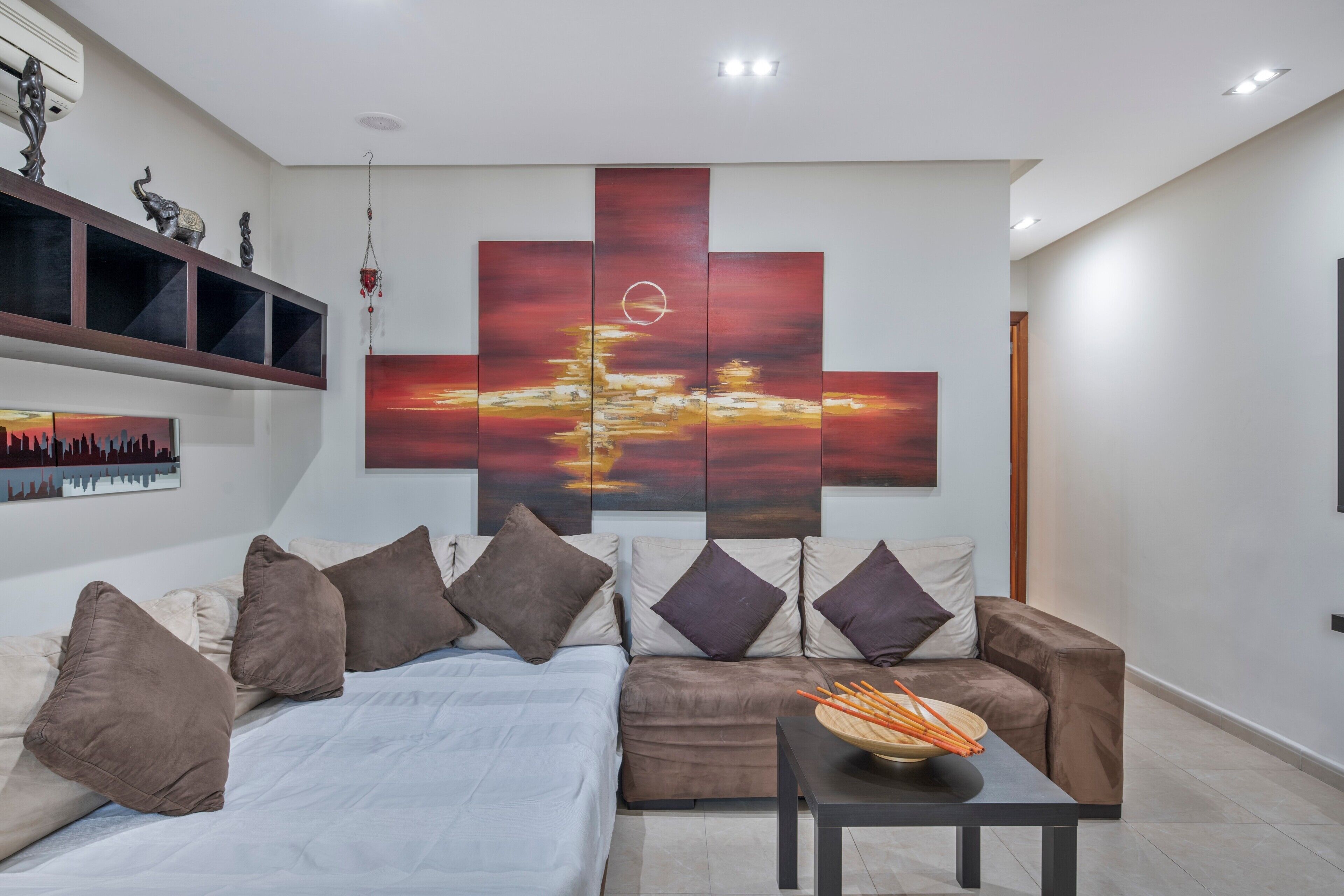 Una sala de estar moderna con un sofá modular, una mesa de centro y un cuadro abstracto grande en la pared.