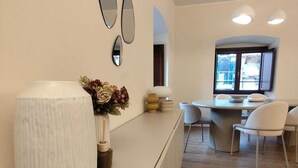 Ein modernes Interieur mit einer weißen Rezeption, einer Blumenvase und einem Essbereich mit Stühlen und einem Tisch.