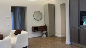 Ein modernes Wohnzimmer mit einem weißen Sofa, Holzboden, einer eingebauten Schrankwand und einem großen Spiegel an der Wand.