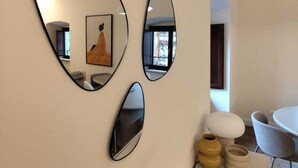 Ein modernes Interieur mit drei ovalen Spiegeln an einer Wand, einem runden Tisch und einem Sofa.