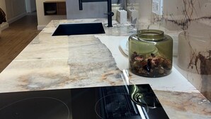 Eine moderne Küche mit Marmorarbeitsplatte, einer schwarzen Dunstabzugshaube und einem eingebauten Backofen.