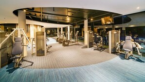 Ein Fitnessstudio mit Herz-Kreislauf-Geräten, Krafttrainingsstationen und einer gewölbten Decke.