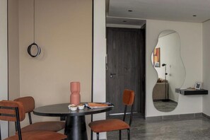 Un espace repas moderne avec une table ronde, des chaises et un miroir mural original.