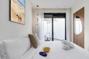Hotellihuone, jossa on sänky, taulu, näkymä ulos ja parveke.