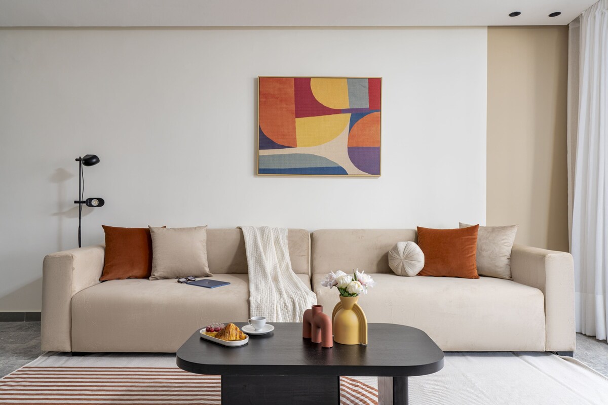 Una sala de estar moderna con un sofá, una mesa de centro y un cuadro abstracto.