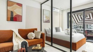 Une chambre d’hôtel moderne, équipée d’un canapé, d’un lit, d’une table basse et ornée d’œuvres d’art sur les murs.