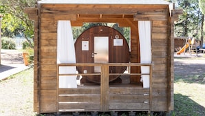 A wooden cabin with a door, a small porch, and a slide in the background. - Mobile Home 'Village Camping De L'Ostriconi 28' with Sea View, Shared Pool and Wi-Fi (Palasca)