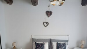 Et soveværelse med en seng, to sengeborde, en hængende lampe og en hjerteformet dekoration på væggen.