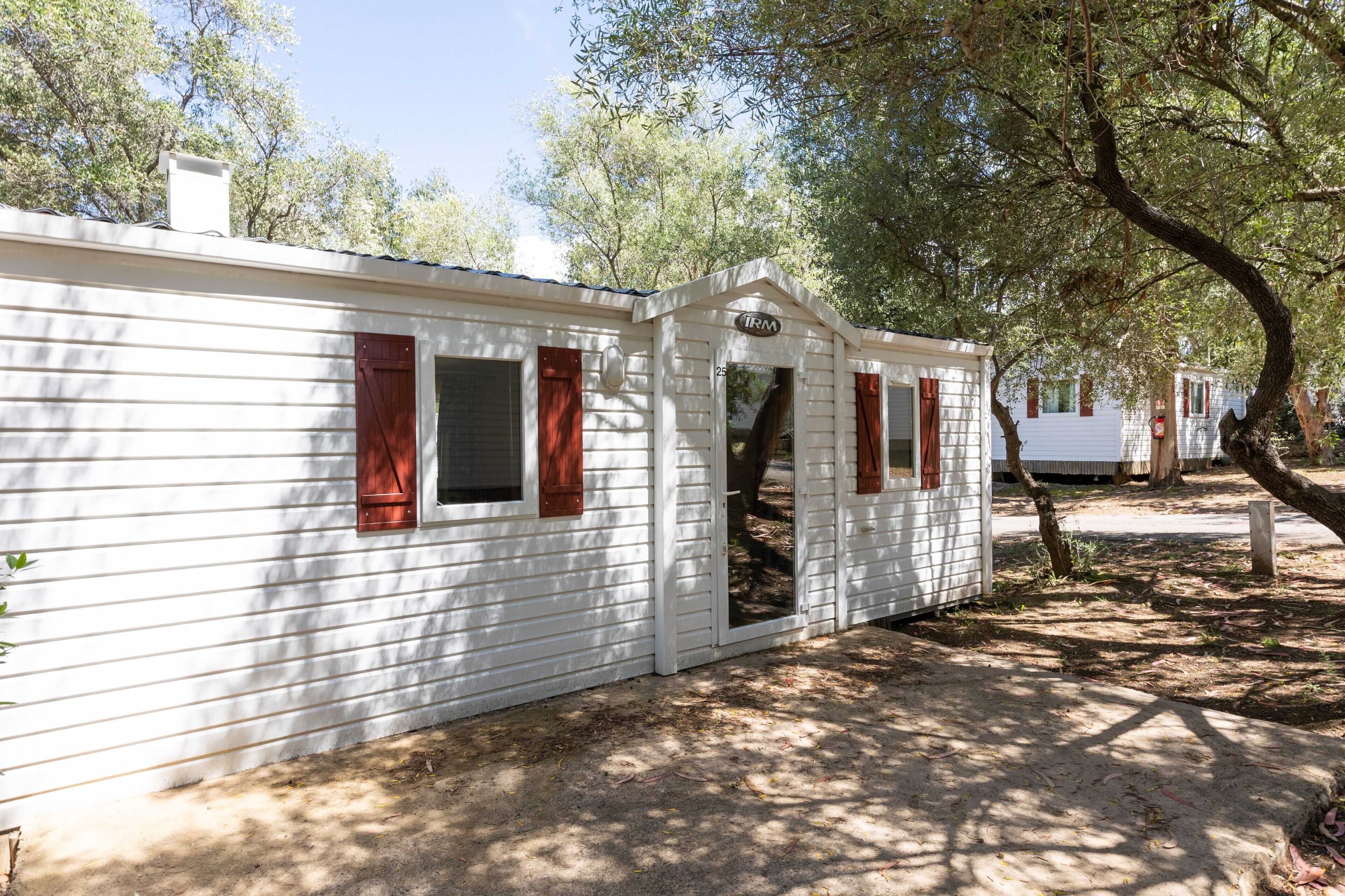 A white mobile home with a chimney, a door, and a window with a shutter.