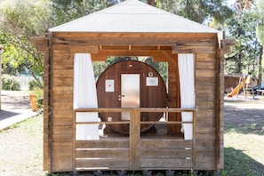 Eine Holzhütte mit Tür, einer kleinen Veranda und einer Rutsche im Hintergrund.