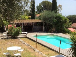 Ein Garten mit Schwimmbecken, einer Holzterrasse und Gartenmöbeln.