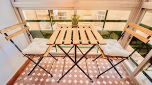 A balcony with a wooden table and chairs, a potted plant, and a patterned floor. - Central | 3 BR | Easy Parking | Ideal for Groups (Granada)