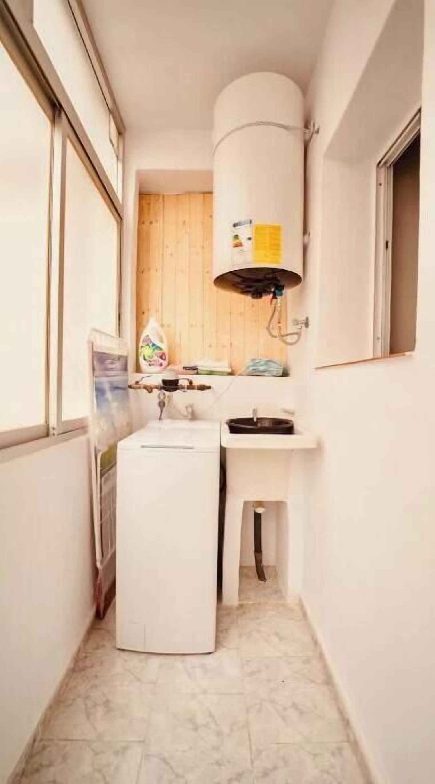 Een kleine badkamer met toilet, wastafel en een witte wasmachine.