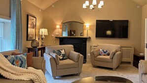 A living room with two sofas, a coffee table, a fireplace, and a TV mounted on the wall. - Property 472 - Kylemore - sleeps 20 guests  in 11 bedrooms (Kylemore)