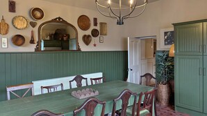 A dining room with a green table, wooden chairs, a chandelier, and various wall decorations. - Property 472 - Kylemore - sleeps 20 guests  in 11 bedrooms (Kylemore)