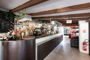 Eine Bar mit einer Theke, Regalen voller Flaschen, Gläsern und einer Kreidetafel mit der Speisekarte.