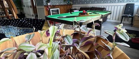 A pool table in a room with patterned wallpaper and a ceiling light.
