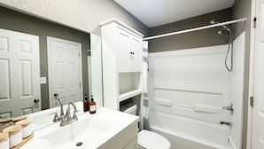 A bathroom with a white sink, mirror, toilet, and bathtub. - 4BR Beautiful Gardner Getaway Game Room Central Location Sleeps 10 (Gardner)