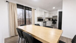 A modern kitchen with white cabinets, a wooden dining table, and black chairs. - 4BR Beautiful Gardner Getaway Game Room Central Location Sleeps 10 (Gardner)