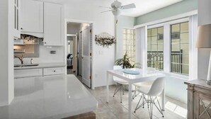 A modern kitchen with white cabinets, a central island, and a dining area with a white table and chairs. - Coastal Oasis on Siesta Key: 1BR Condo + Boat Dock Access (Sarasota)