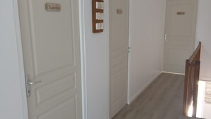 A hallway with three doors, each labeled with a nameplate. The walls are plain, and the floor is wooden. - The Gartempe Cottage (Saint-Sornin-la-Marche)