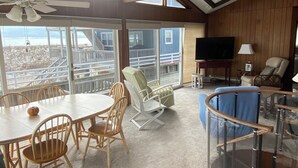 Een kamer met een balkon, een televisie en een eethoek met stoelen en een tafel.