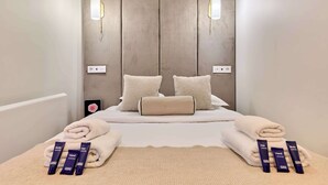 A hotel room with a bed, two wall-mounted light fixtures, a bedside table with toiletries, and a phone on the nightstand. - Stunning apartment with AC - Center of Paris (Paris)