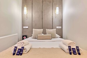A hotel room with a bed, two wall-mounted light fixtures, a bedside table with toiletries, and a phone on the nightstand. - Stunning apartment with AC - Center of Paris (Paris)