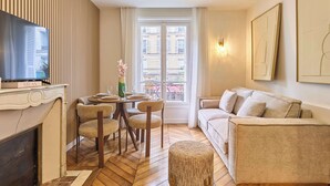 A living room with a fireplace, a dining area, a sofa, and a television. - Stunning apartment with AC - Center of Paris (Paris)