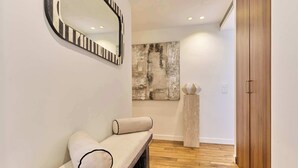 A hallway with a bench, a mirror, a large abstract painting, and a wooden door. - Stunning apartment with AC - Center of Paris (Paris)