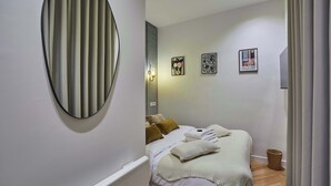 Un dormitorio con cama, luz empotrada en la pared y una obra de arte.