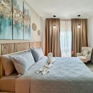 Ein Hotelzimmer mit einem großen Bett, einem Sessel, einer Wand mit abstrakter Kunst und einem Fenster mit Vorhängen.
