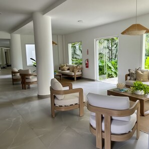 Eine geräumige Lobby mit moderner Einrichtung, großen Fenstern und Blick auf Grünflächen.