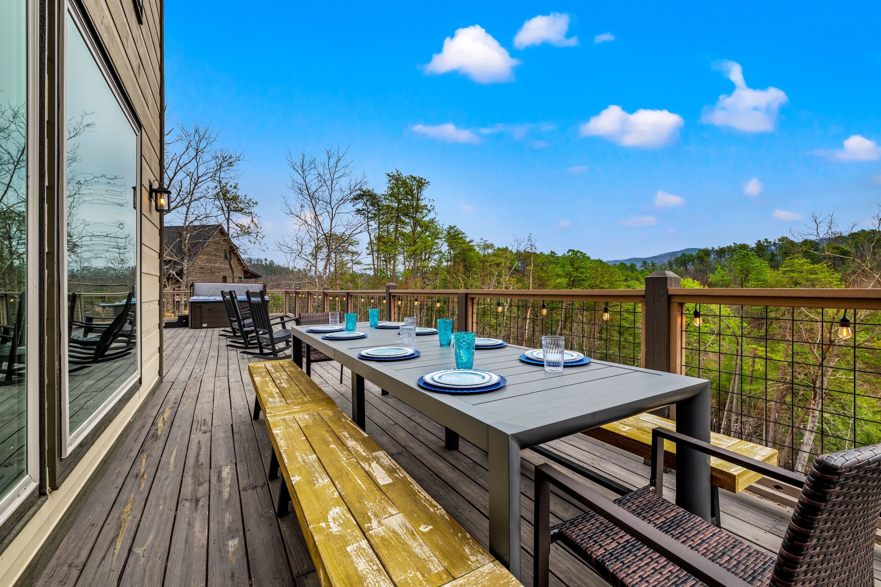A deck with a table set for dining, outdoor seating, and a view of the surrounding landscape.