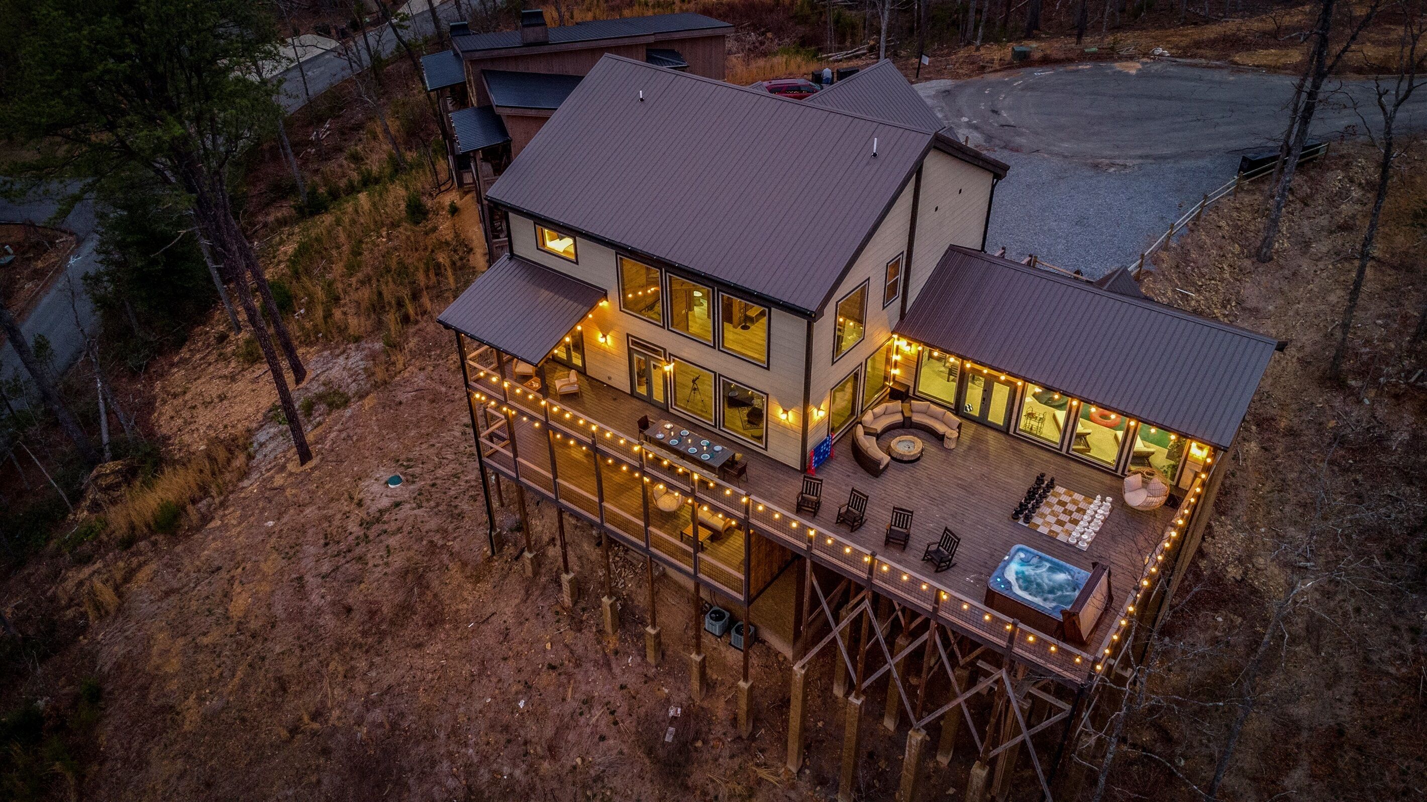 A two-story house with a deck, outdoor seating, and a hot tub.