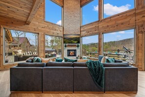 Ein geräumiges Wohnzimmer mit Kamin, großen Fenstern und Blick ins Freie.