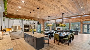 Une cuisine spacieuse dotée d’un grand îlot central, d’un plafond en bois et d’un éclairage moderne.