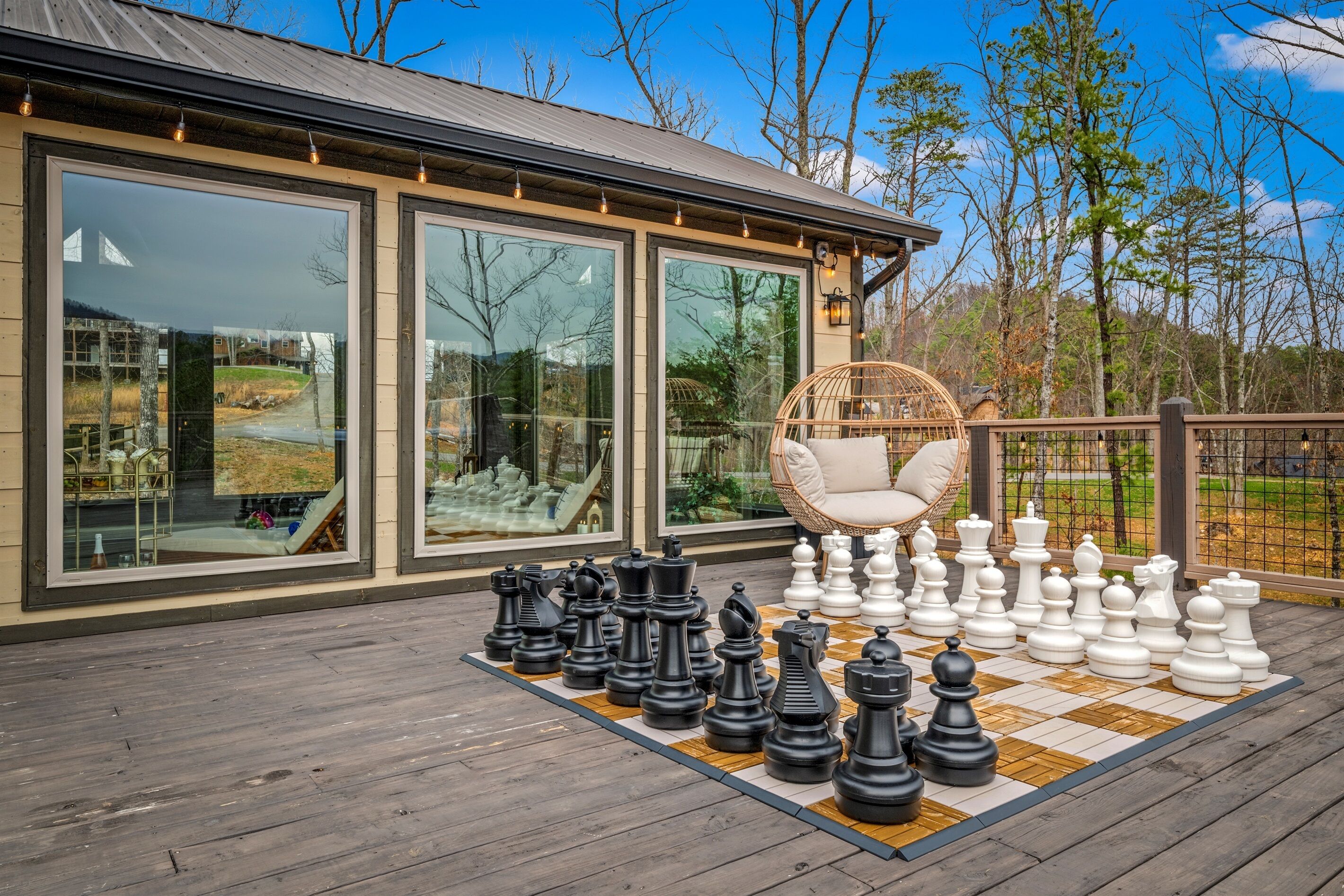 A deck with a chessboard and large windows overlooking a landscape.